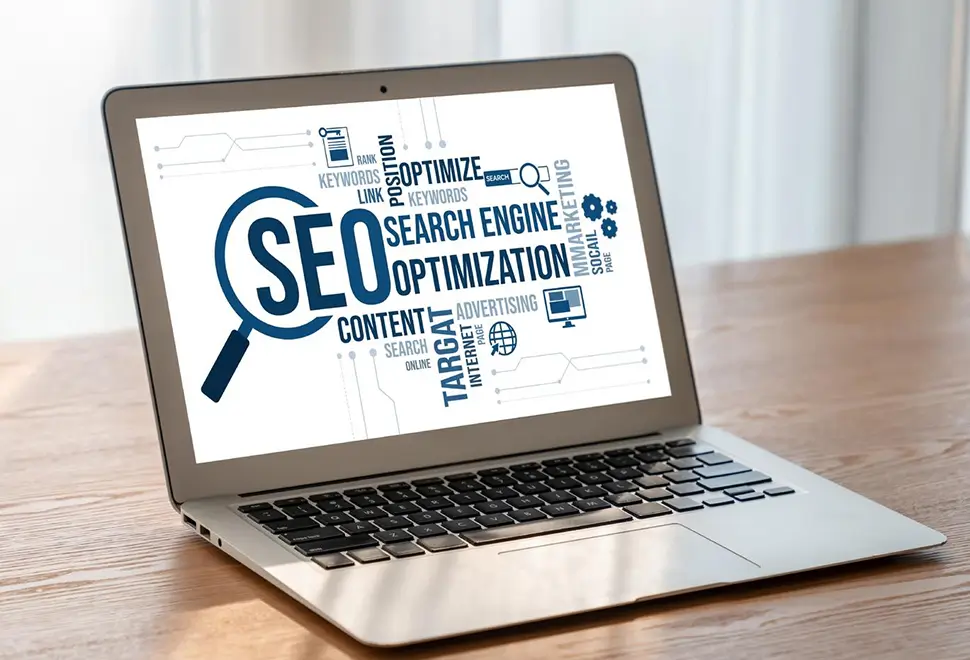 Laptop displaying a word cloud related to SEO, including terms like search engine optimization, keywords, content, and marketing